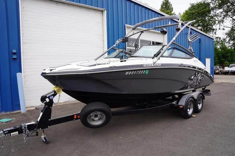 Slide: The Image of 2014 Yamaha Boats 212X on trailer, parked outside blue building. - 2