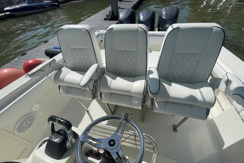 Slide: The Image of 2004 Hydra-Sports Vector 3300 CC boat interior with three white cushioned seats and steering wheel. - 21