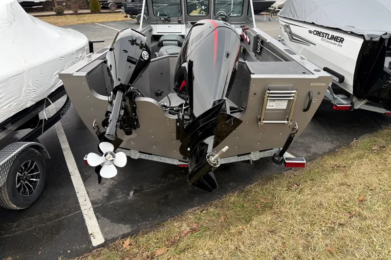 Slide: The Image of 2026 Crestliner 1850 Commander boat with dual outboard motors in a parking lot. - 17