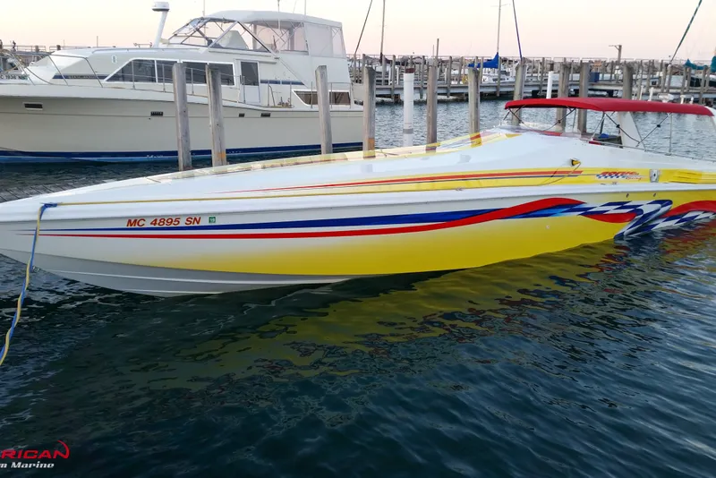 The Image of 2000 Sonic 45 SS speedboat with vibrant yellow and red design docked at marina. - 0