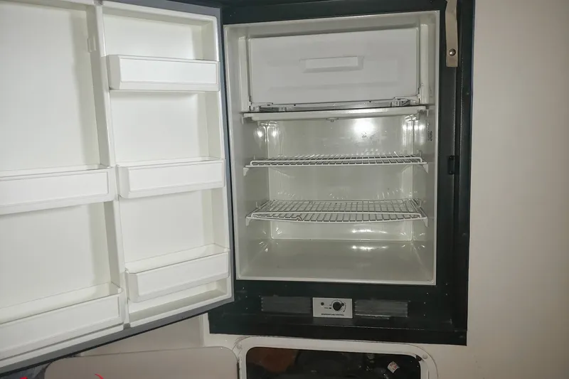 Slide: The Image of Open refrigerator in a 2000 Sonic 45 SS boat, showing empty shelves and door compartments. - 7