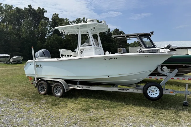 The Image of 2017 Sea Hunt Ultra 211 boat on trailer, parked on grass with trees in background. - 0
