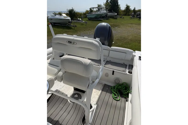 Slide: The Image of 2017 Sea Hunt Ultra 211 boat interior with seating and motor, docked on grassy area. - 6