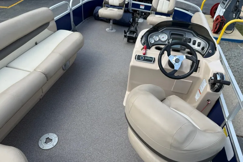 Slide: The Image of 2016 Sun Tracker Fishin' Barge 20 DLX interior with beige seating and steering console. - 19