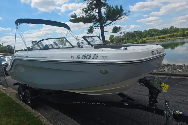 Slide: The Image of 2020 Bayliner DX 2250 boat on trailer by a lake under a blue sky. - 8