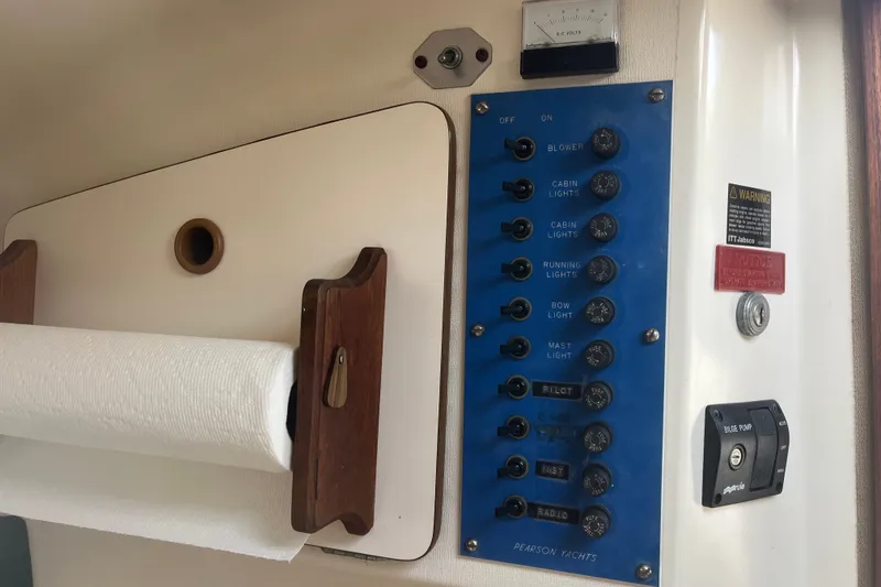 Slide: The Image of Electrical panel of a 1976 Pearson 10M yacht with switches and paper towel holder. - 25