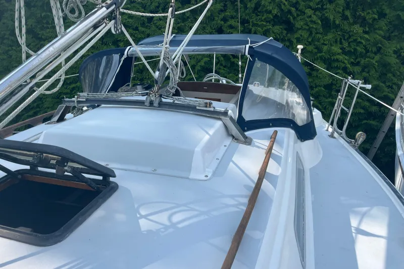 Slide: The Image of 1976 Pearson 10M sailboat deck with ropes and canopy, surrounded by greenery. - 17