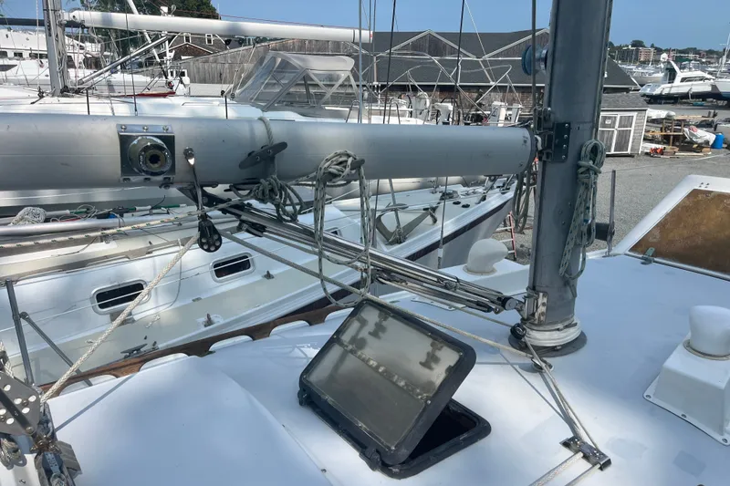 Slide: The Image of 1976 Pearson 10M sailboat deck with rigging and open hatch in a marina. - 13