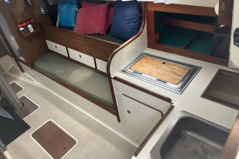 Slide: The Image of Interior of a 1976 Pearson 10M sailboat with seating, cushions, and compact kitchen area. - 21