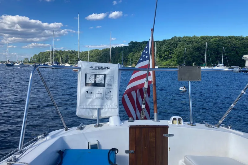 Slide: The Image of Sailboat deck view with American flag, Lifesling, and scenic harbor background. - 37