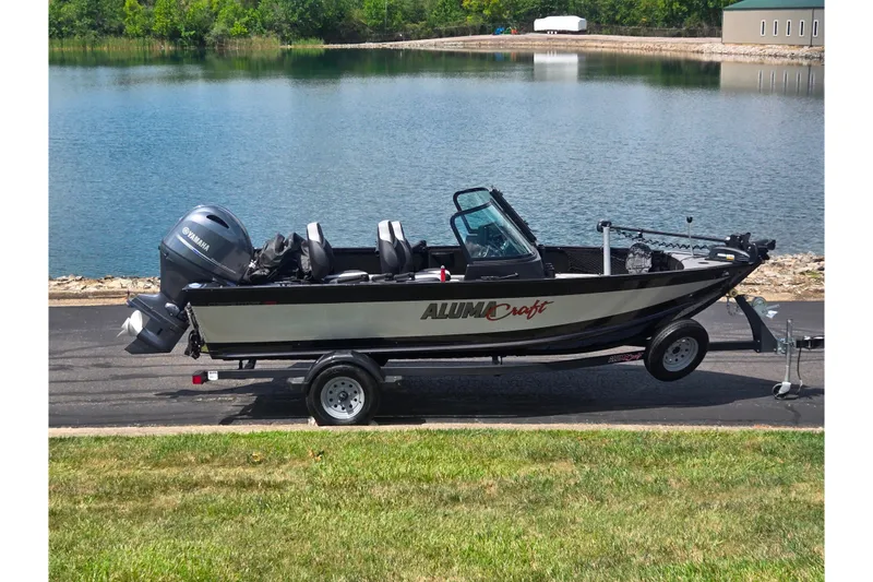 The Image of 2023 Alumacraft Competitor 165 Sport boat on trailer by a lake. - 0