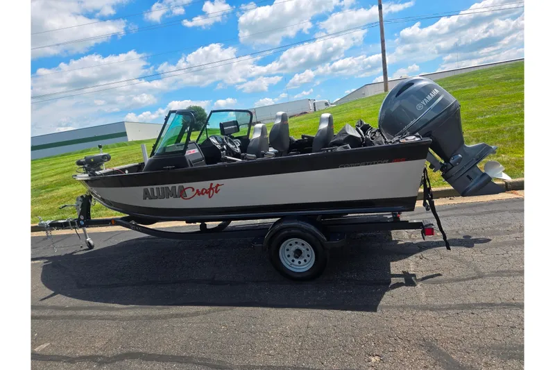 Slide: The Image of 2023 Alumacraft Competitor 165 Sport boat on trailer, parked outdoors under a blue sky. - 4