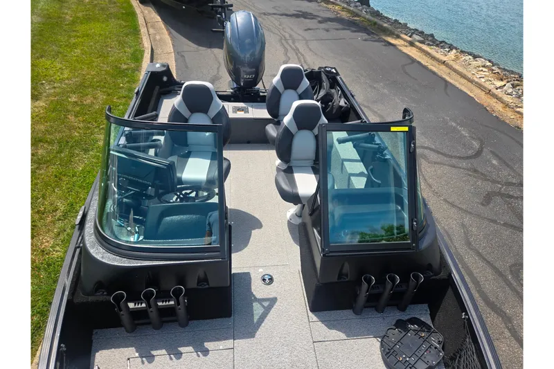 Slide: The Image of 2023 Alumacraft Competitor 165 Sport boat with seating and windshield, parked near water. - 20