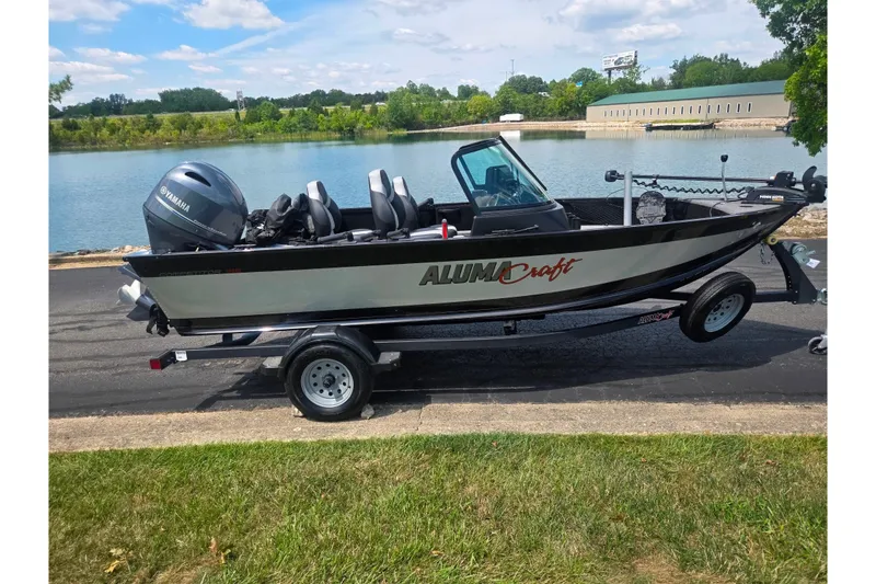 Slide: The Image of 2023 Alumacraft Competitor 165 Sport boat on trailer by a lake. - 10