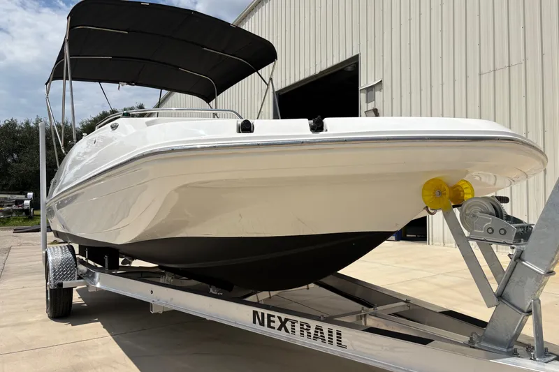 Slide: The Image of 2022 Hurricane SunDeck Sport 201 OB boat on trailer, parked outside a building. - 13