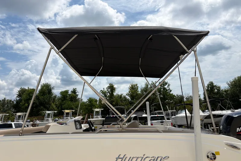 Slide: The Image of 2022 Hurricane SunDeck Sport 201 OB boat with canopy, parked outdoors under cloudy sky. - 18
