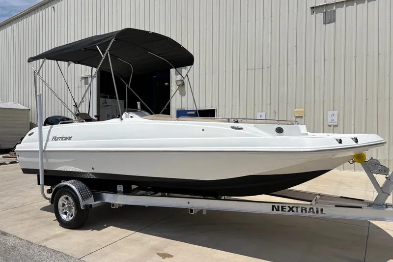 Slide: The Image of 2022 Hurricane SunDeck Sport 201 OB boat on trailer, parked outside a warehouse. - 3
