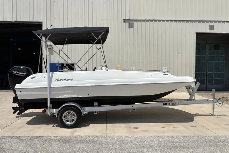Slide: The Image of 2022 Hurricane SunDeck Sport 201 OB boat on trailer, parked outside a building. - 1