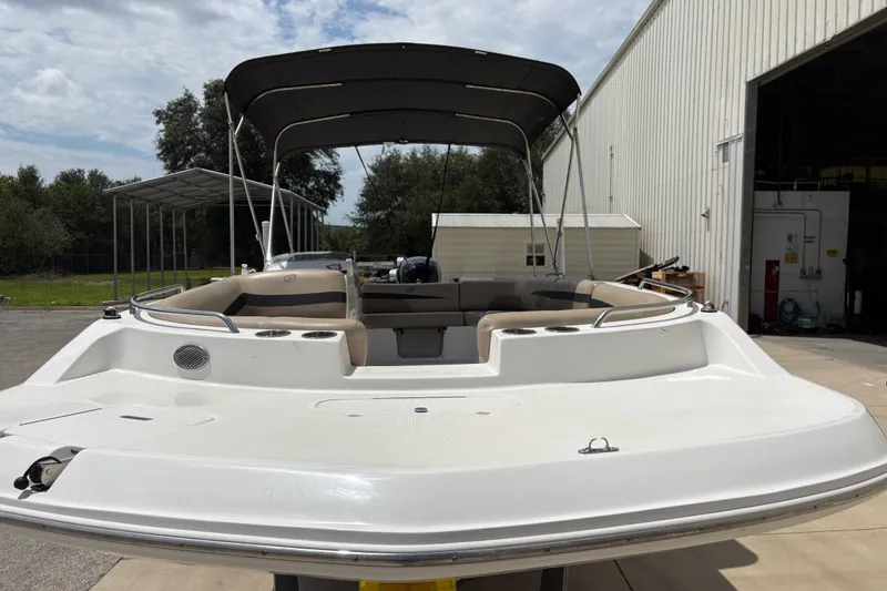 Slide: The Image of 2022 Hurricane SunDeck Sport 201 OB boat with canopy, docked near a warehouse. - 11