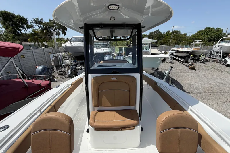 Slide: The Image of 2023 Sea Hunt Ultra 275SE boat interior with tan seating, parked in a marina. - 13