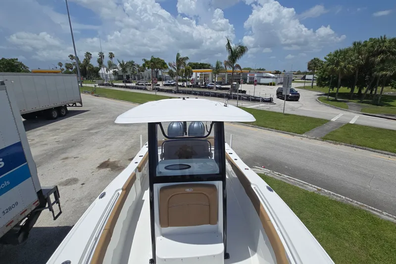 Slide: The Image of 2023 Sea Hunt Ultra 275SE boat parked near a road with palm trees and cloudy sky. - 22