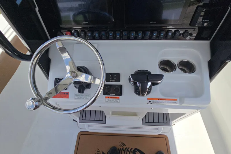 Slide: The Image of 2023 Sea Hunt Ultra 275SE helm with steering wheel, controls, and cup holders. - 26