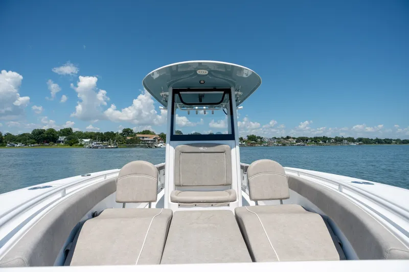 Slide: The Image of 2024 Sea Hunt Ultra 265SE boat on calm water under clear blue sky. - 11