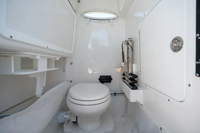 Slide: The Image of 2024 Sea Hunt Ultra 265SE boat interior bathroom with toilet and storage. - 15