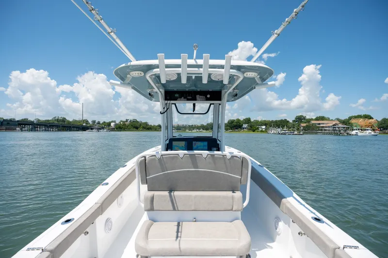 Slide: The Image of 2024 Sea Hunt Ultra 265SE boat on calm water under a clear blue sky. - 30