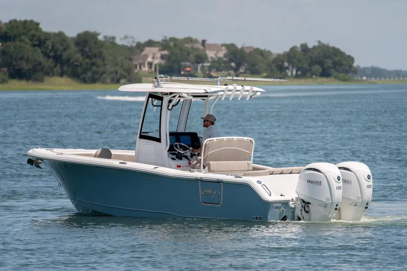 Slide: The Image of 2024 Sea Hunt Ultra 265SE boat cruising on a serene lake with dual Yamaha engines. - 2