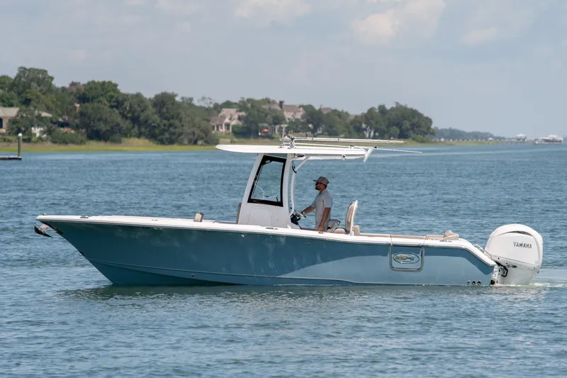 Slide: The Image of 2024 Sea Hunt Ultra 265SE boat cruising on a calm lake with scenic background. - 1