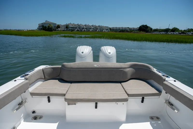 Slide: The Image of 2024 Sea Hunt Ultra 265SE boat with cushioned seating, dual engines, and scenic water view. - 25