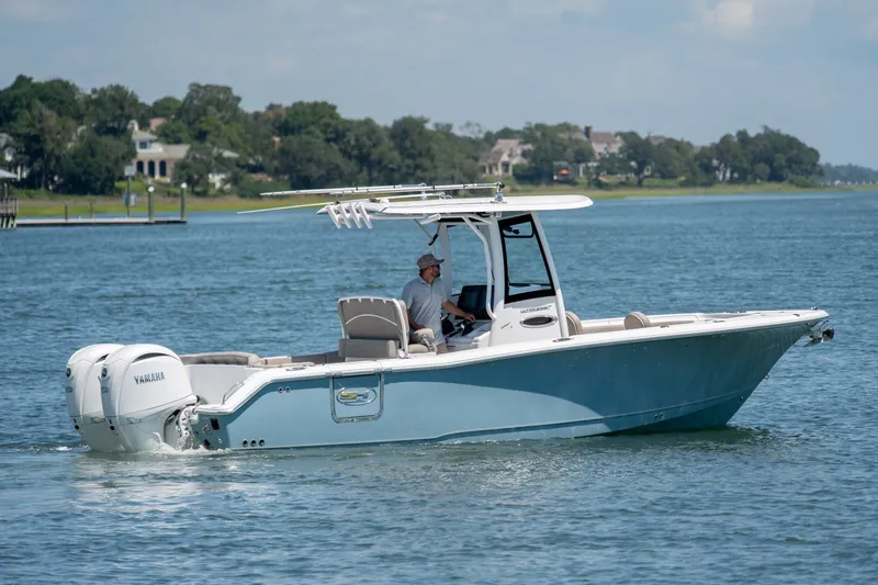 Slide: The Image of 2024 Sea Hunt Ultra 265SE boat cruising on a serene lake with Yamaha engines. - 4