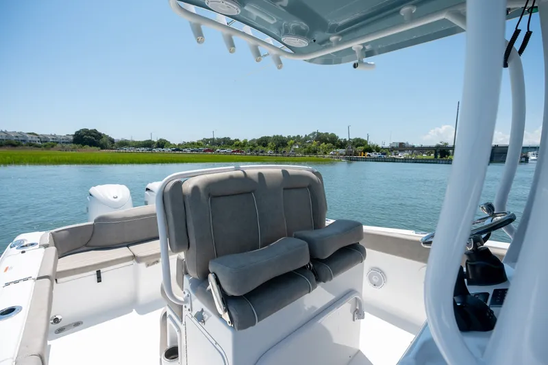 Slide: The Image of 2024 Sea Hunt Ultra 265SE boat interior with seating, on a calm waterway. - 16