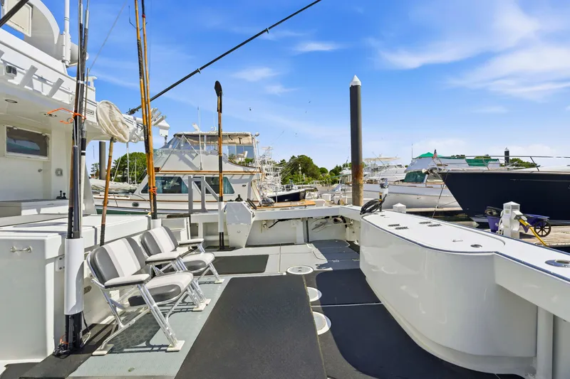 Slide: The Image of Fishing deck of a 2018 Dixon 55 yacht, featuring chairs and fishing rods at a marina. - 51