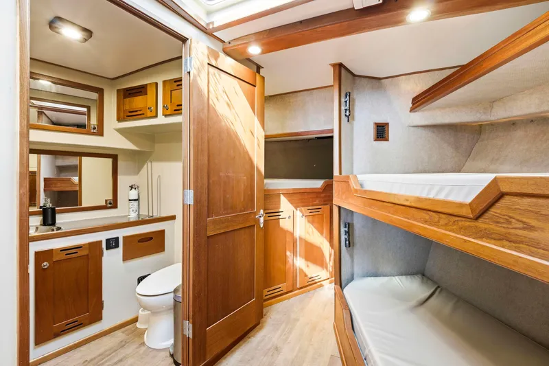 Slide: The Image of Interior of 2018 Dixon 55 yacht featuring wooden cabinetry, bunk beds, and a compact bathroom. - 43