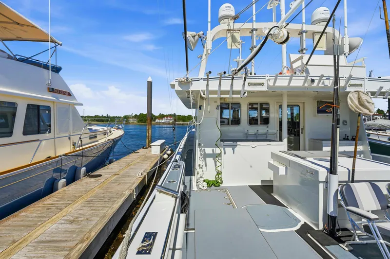Slide: The Image of Docked Dixon 55 boat from 2018, with clear blue sky and calm waters. - 25