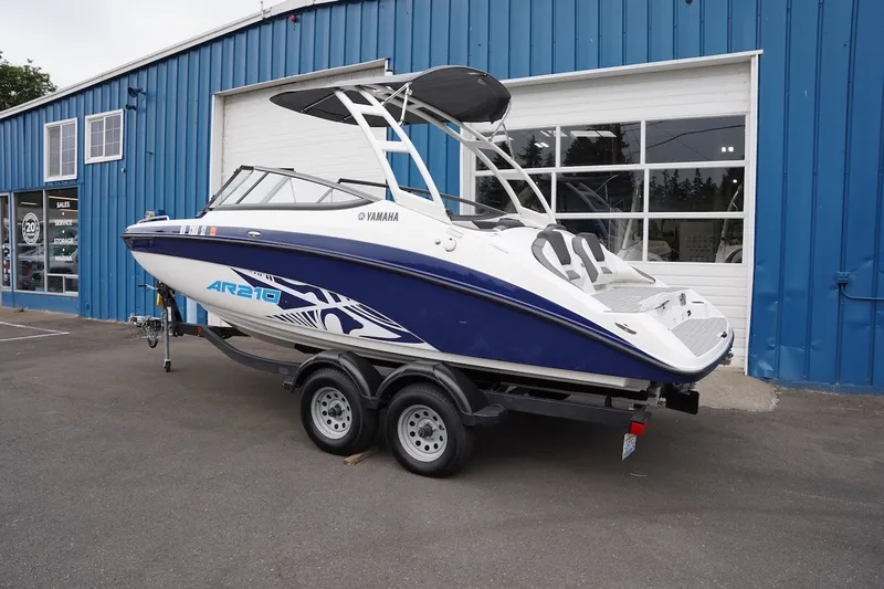 Slide: The Image of 2022 Yamaha AR210 boat on trailer outside blue building. - 1