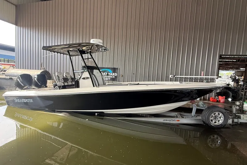 Slide: The Image of 2020 ShearWater 270 Carolina Flare boat in a marina, black hull, on a trailer. - 34