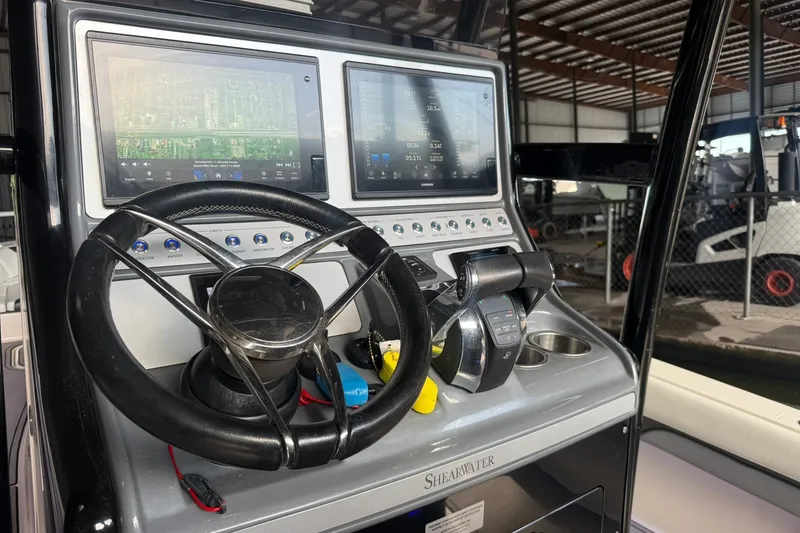 Slide: The Image of 2020 ShearWater 270 Carolina Flare boat dashboard with steering wheel and navigation screens. - 13