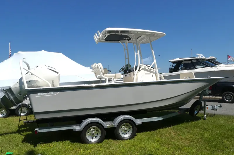 Slide: The Image of 2027 Boston Whaler 210 Montauk boat on trailer, displayed outdoors under clear blue sky. - 2