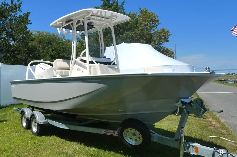 The Image of 2027 Boston Whaler 210 Montauk boat on trailer, parked on grass, under clear sky. - 0