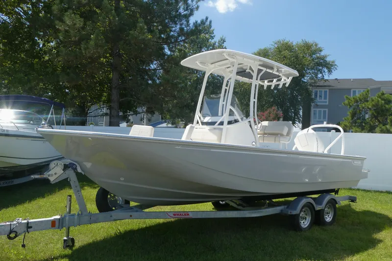 Slide: The Image of 2027 Boston Whaler 210 Montauk boat on trailer, parked on grass under clear sky. - 1