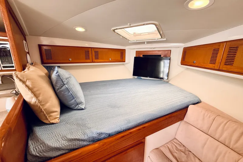 Slide: The Image of Interior cabin of 2004 Cabo 35 Express with bed, TV, and wooden storage cabinets. - 19