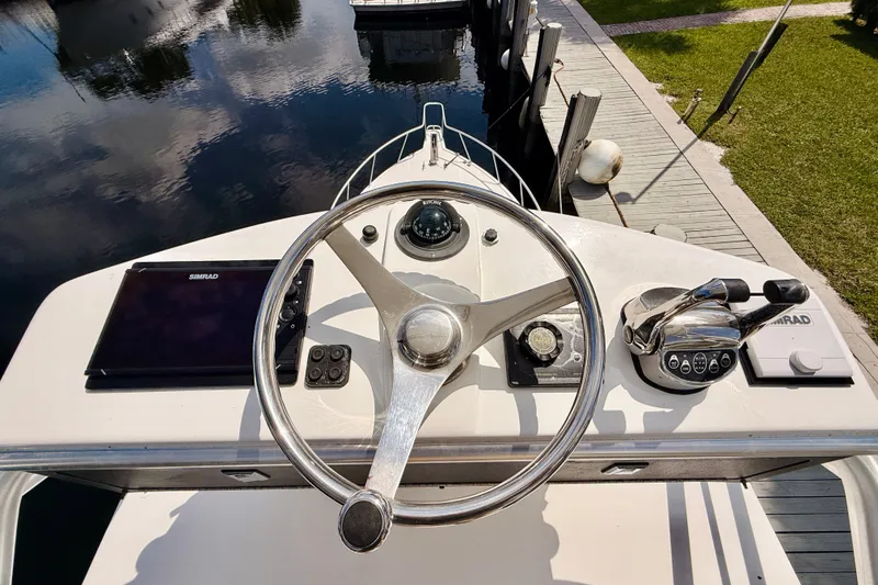 Slide: The Image of Steering wheel and controls of a 2004 Cabo 35 Express boat at dock. - 44