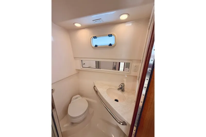 Slide: The Image of 2004 Cabo 35 Express boat bathroom with toilet, sink, and porthole window. - 25