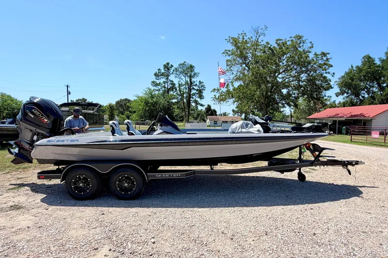 The Image of 2027 Skeeter ZXE21 boat on trailer, parked outdoors under clear blue sky. - 0