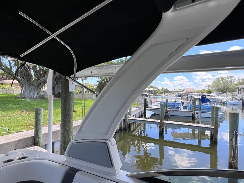Slide: The Image of 2022 Chaparral 267 SSX OB boat interior with marina view, featuring sleek design and canopy. - 39