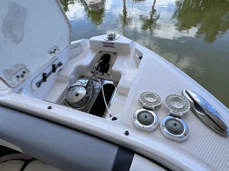 Slide: The Image of 2022 Chaparral 267 SSX OB boat anchor compartment with open hatch, docked on calm water. - 37