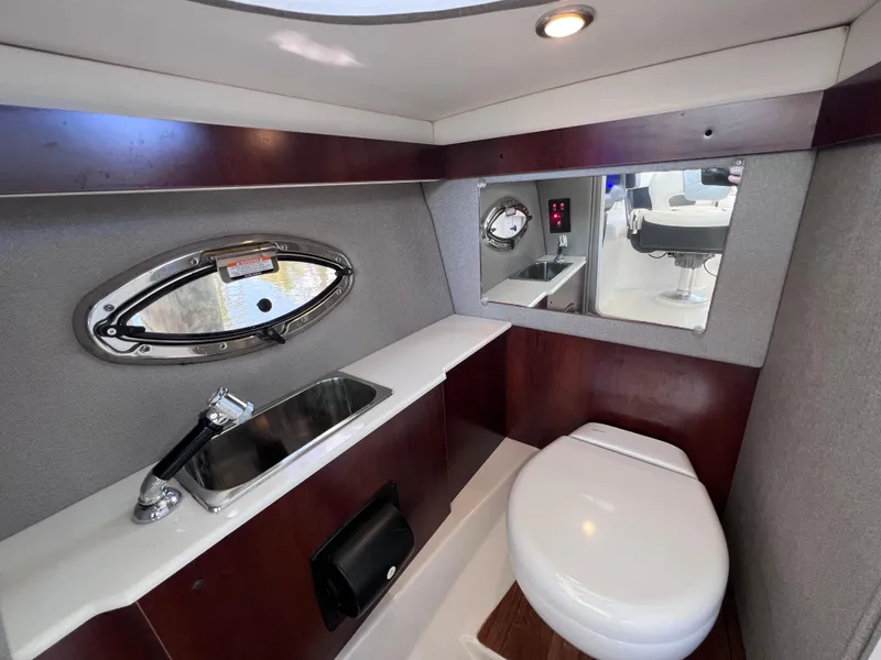 Slide: The Image of 2022 Chaparral 267 SSX OB boat bathroom with sink, toilet, and mirror. - 26